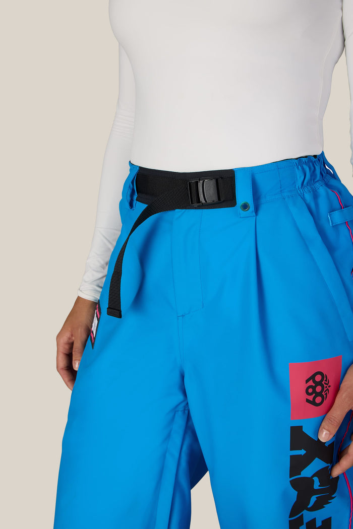 A person wearing bright blue 686 Women’s Fox Racing 97 Shell Pants with a black webbing belt.