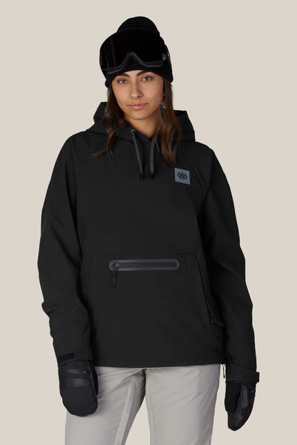 Wearing the 686 Women’s Waterproof Hoody, a person stands facing forward with a neutral expression against a plain background, paired with a beanie, ski goggles, and gloves.
