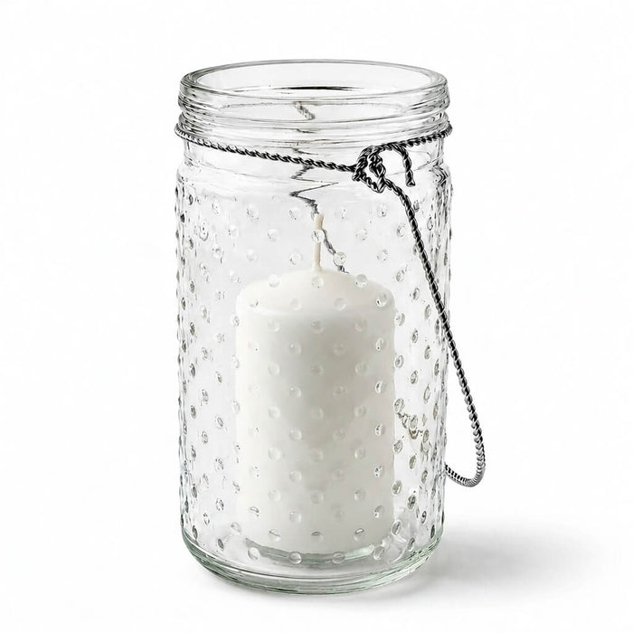 7.5 inch hanging dotted glass jar with handle and an unlit pillar candle inside