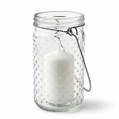 7.5 inch hanging dotted glass jar with handle and an unlit pillar candle inside