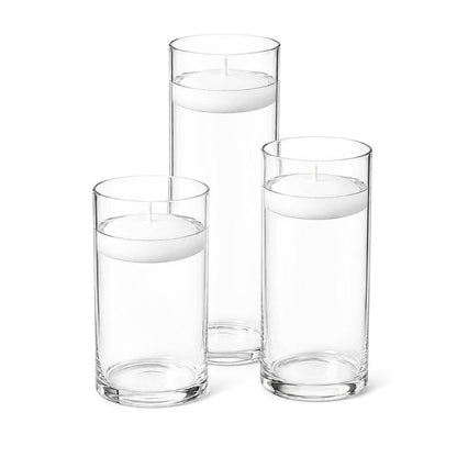 Three white floating candles in cylindrical glass vases filled with water