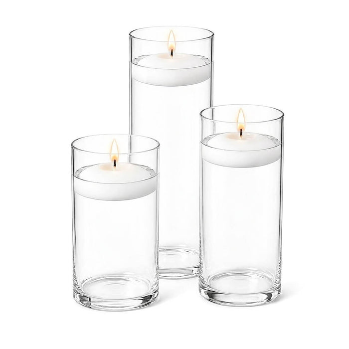 Three lit white floating candles in cylindrical glass vases filled with water