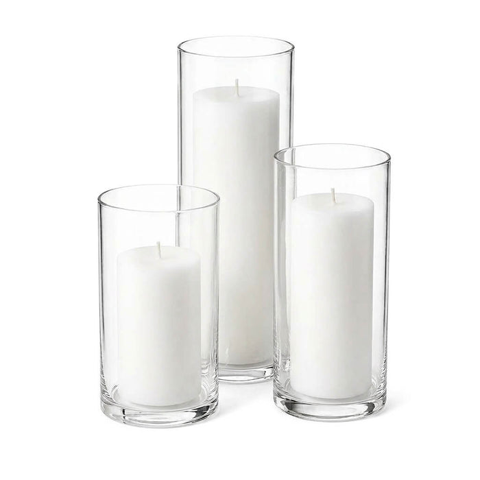 Three white pillar candles in clear glass cylinder vases