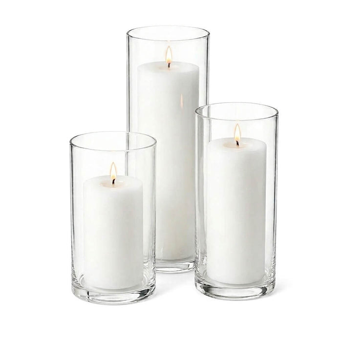Three lit white pillar candles in glass cylinder vases