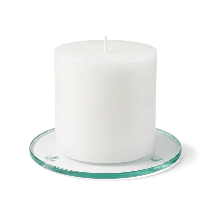 An unlit white pillar candle on a clear glass Round Coaster 4" against a white backdrop