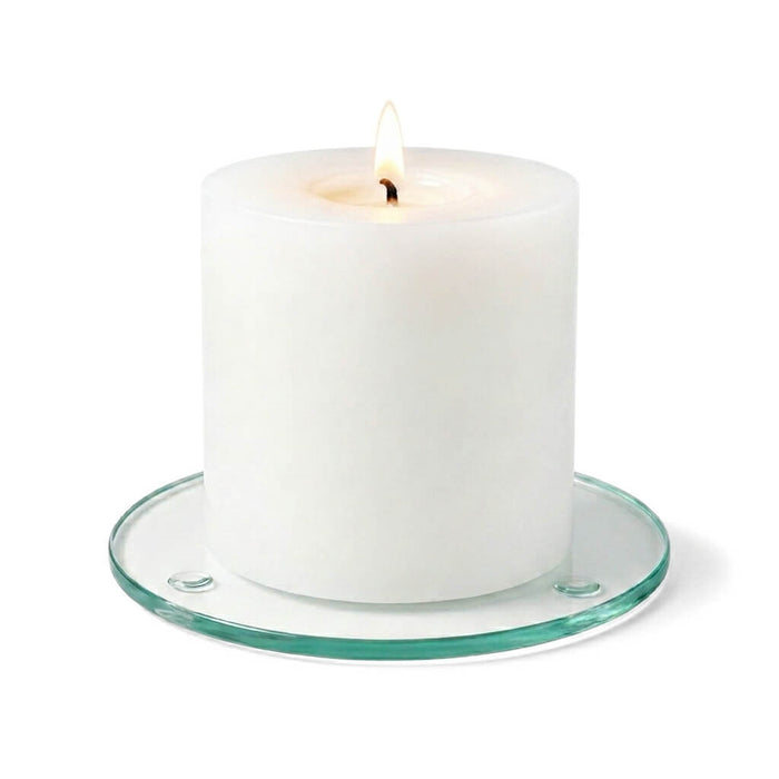 A lit white pillar candle on a clear glass Round Coaster 4" against a white backdrop