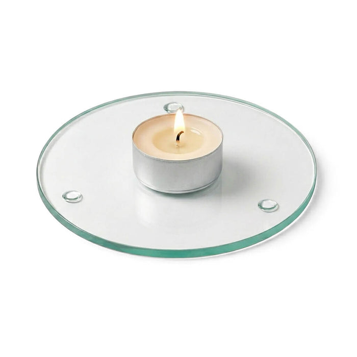 A lit tealight candle on a clear glass Round Coaster 4" against a white backdrop