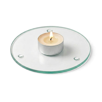 A lit tealight candle on a clear glass Round Coaster 4" against a white backdrop