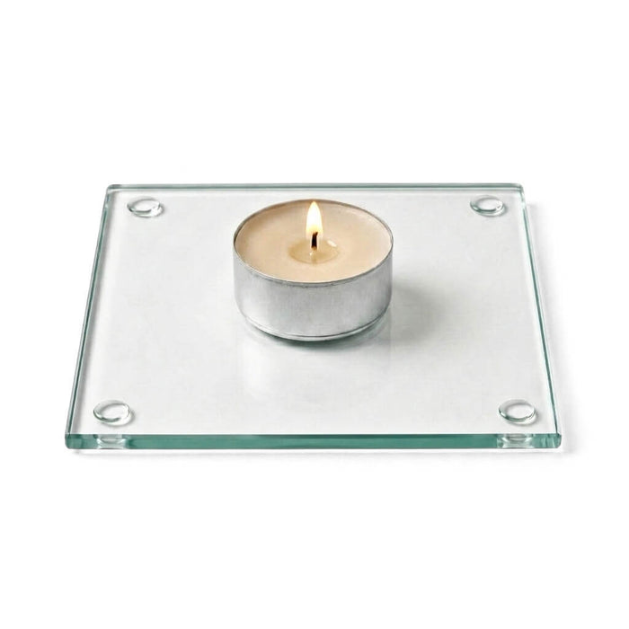 A clean product studio shot of a lit candle sitting on a clear glass Square Coaster 4"