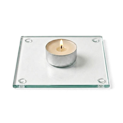 A clean product studio shot of a lit candle sitting on a clear glass Square Coaster 4"