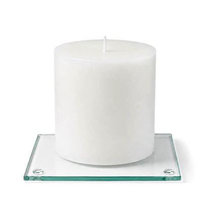 An unlit white pillar candle centered on a clear glass Square Coaster 4" on white background