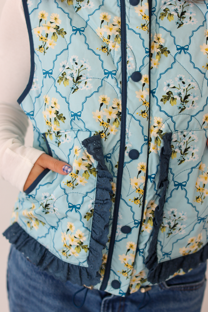 Close up of blue floral print on vest and ruffle pockets