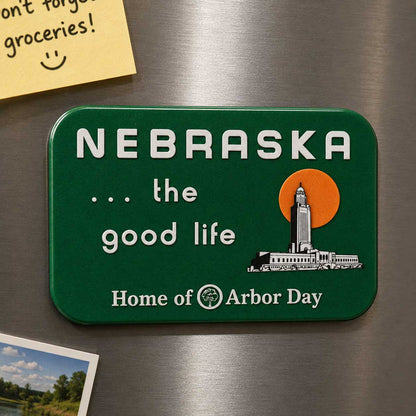 A green rectangular refrigerator magnet with rounded corners featuring the text 'NEBRASKA .