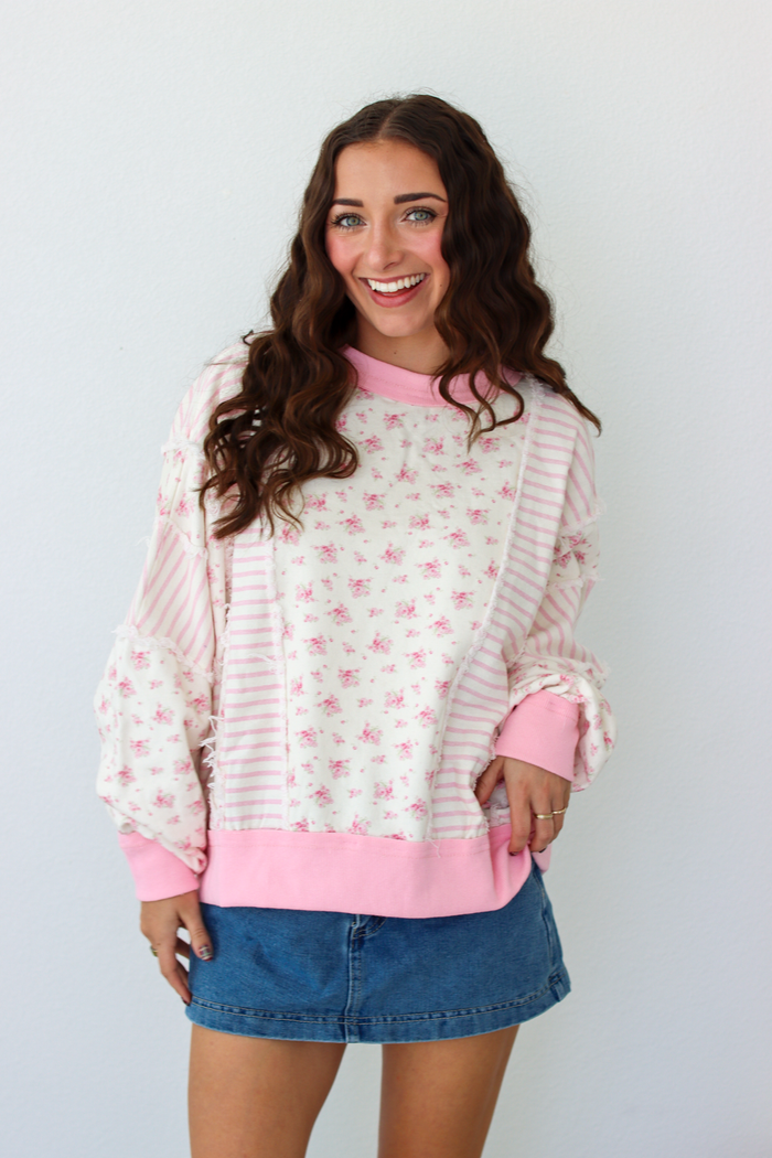 Woman wearing a pink patchwork distressed sweater with a blue denim mini skirt