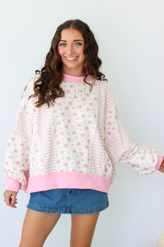 Woman wearing a pink patchwork distressed sweater with a blue denim mini skirt