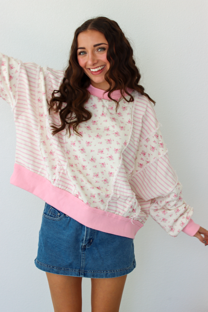 Woman wearing a pink patchwork distressed sweater with a blue denim mini skirt