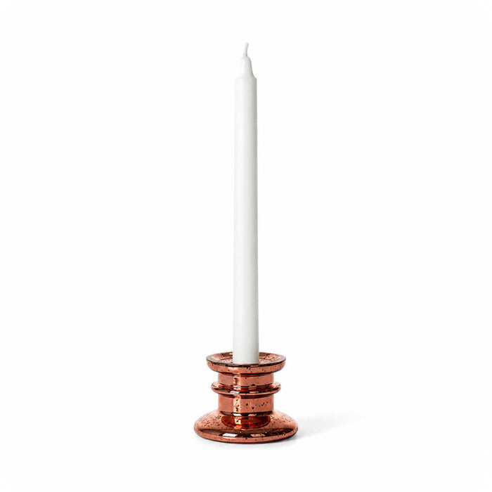 A rose gold taper candle holder with a white taper candle