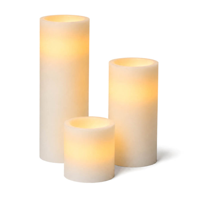 Assorted glowing white LED pillar candles on a white background