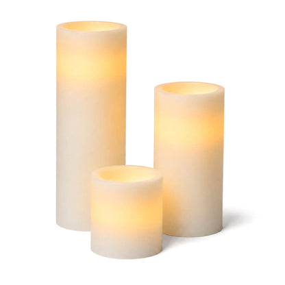 Assorted glowing white LED pillar candles on a white background