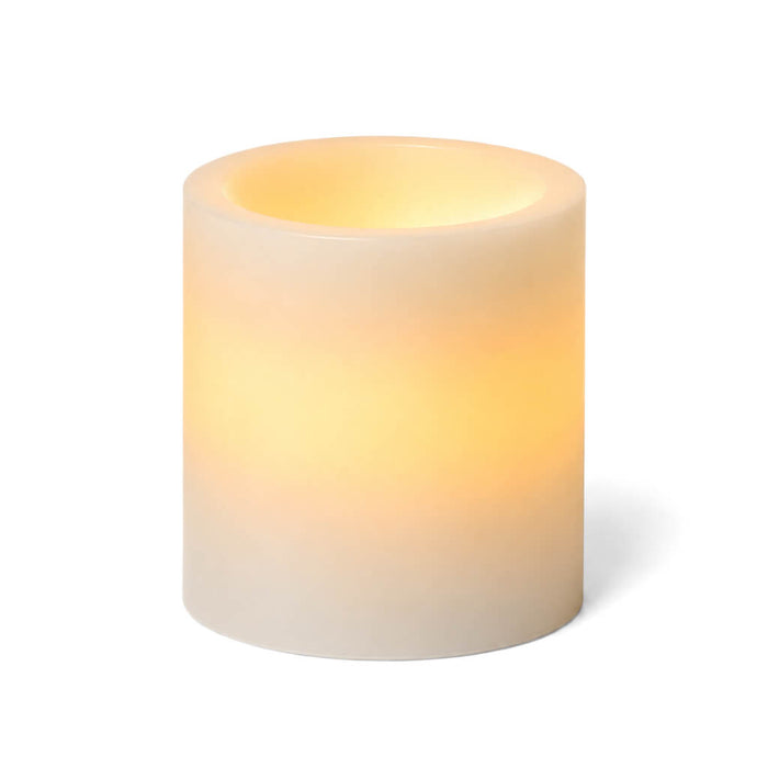 A short glowing ivory flameless LED pillar candle on a white background
