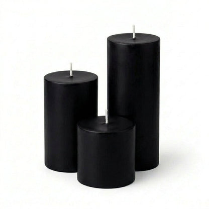 Three black candles of different sizes on a white background
