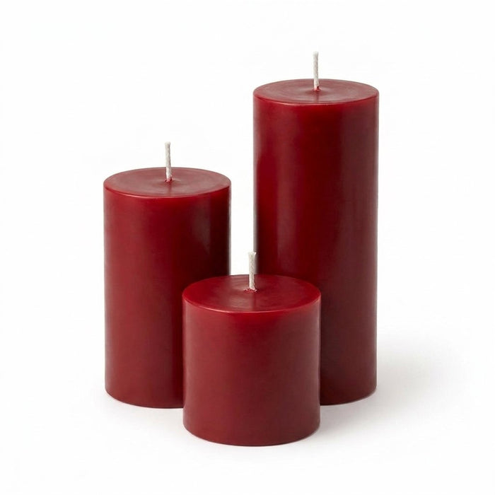 Three unlit red pillar candles in staggered heights on a white backdrop