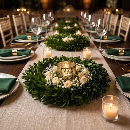 An 8-inch preserved boxwood wreath centerpiece with white roses, greenery, and a gold candle holder