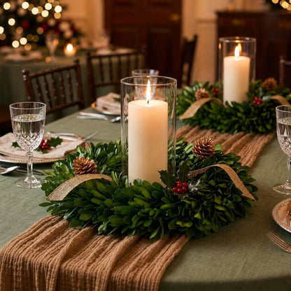 Preserved boxwood wreath surrounding a lit pillar candle on a holiday dining table setting