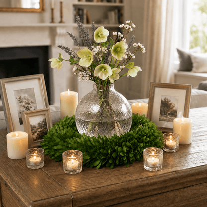 Preserved boxwood wreath framing a flower vase, surrounded by candles and wooden picture frames