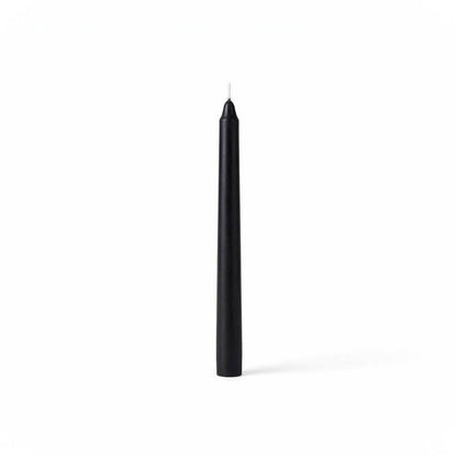 Single black taper candle on clean white backdrop