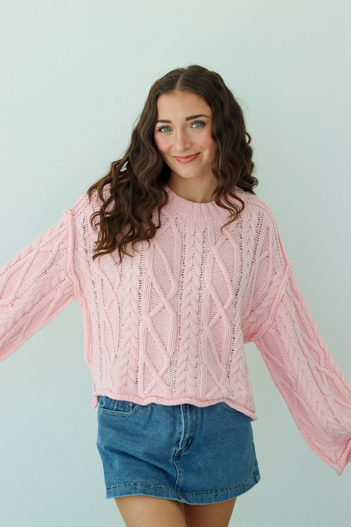 Woman wearing a pink knit sweater with a blue denim mini skirt
