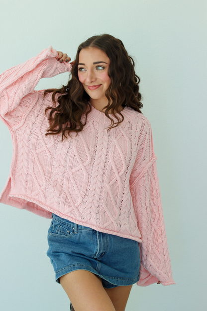 Woman wearing a pink knit sweater with a blue denim mini skirt