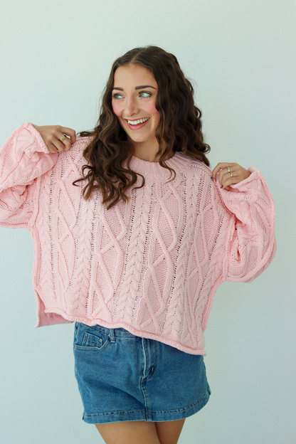Woman wearing a pink knit sweater with a blue denim mini skirt
