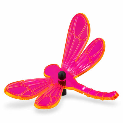 A translucent dragonfly-shaped garden ornament with vibrant pink wings and a bright orange border, mounted on a black pole against a white background.